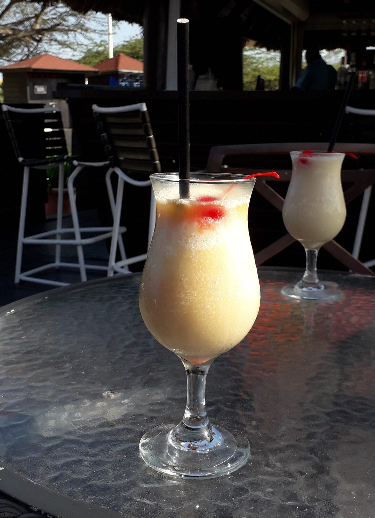 Two pina colada cocktails at a beach bar in Aruba, the kind included at an all-inclusive open bar