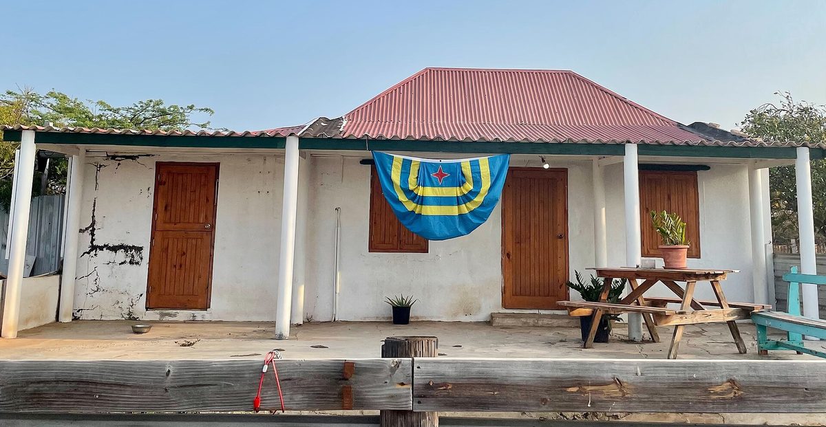 The flag of Aruba displayed on a traditional cunucu house