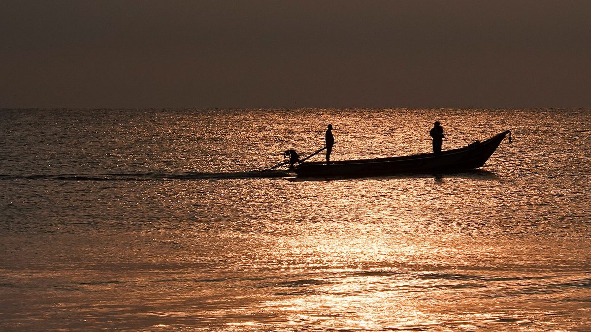 A fishing boat heads out over calm water at sunrise, as charters do off Aruba