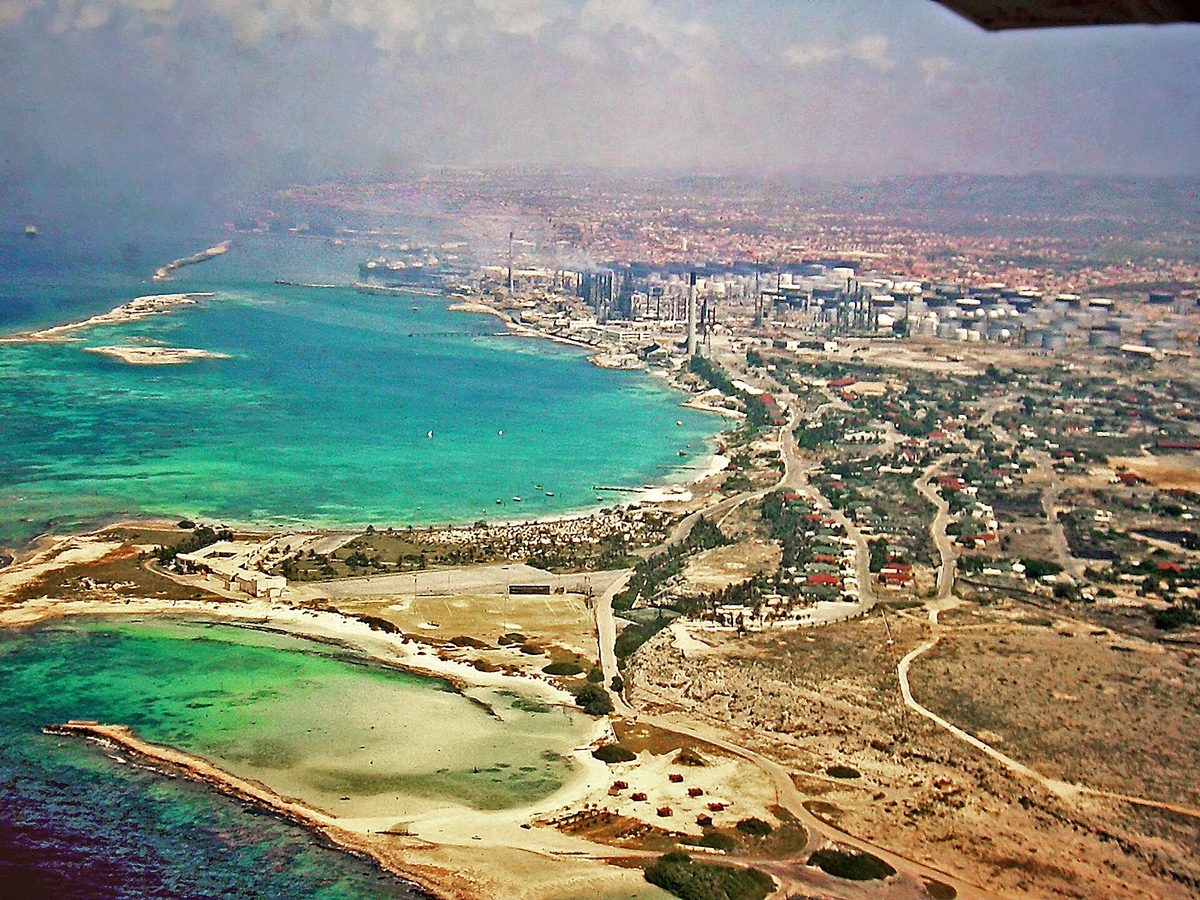 Aerial view of the calm crescent lagoon at Baby Beach, Aruba, with Rodgers Beach and the old San Nicolas refinery beyond