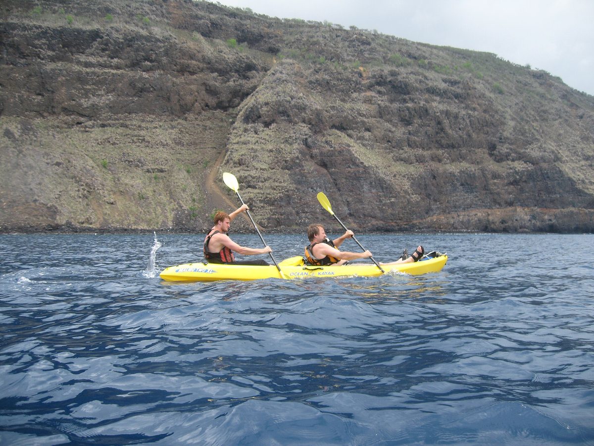 Two paddlers in a tandem sea kayak on calm clear coastal water