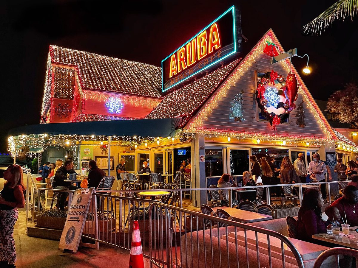 A lively open-air beach bar lit up at night in Aruba, where drinks and dinner add up fast