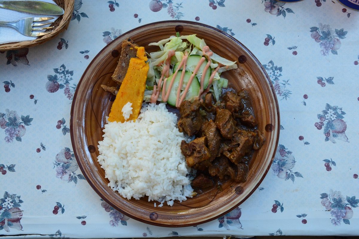 A hearty plate of Aruban stoba with rice and funchi, a slow-cooked Caribbean stew