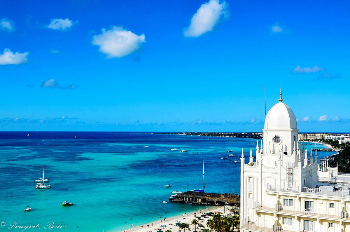 A white-domed resort tower above the turquoise sea in Aruba, where the room rate, tourist levy and service charge all land on your folio
