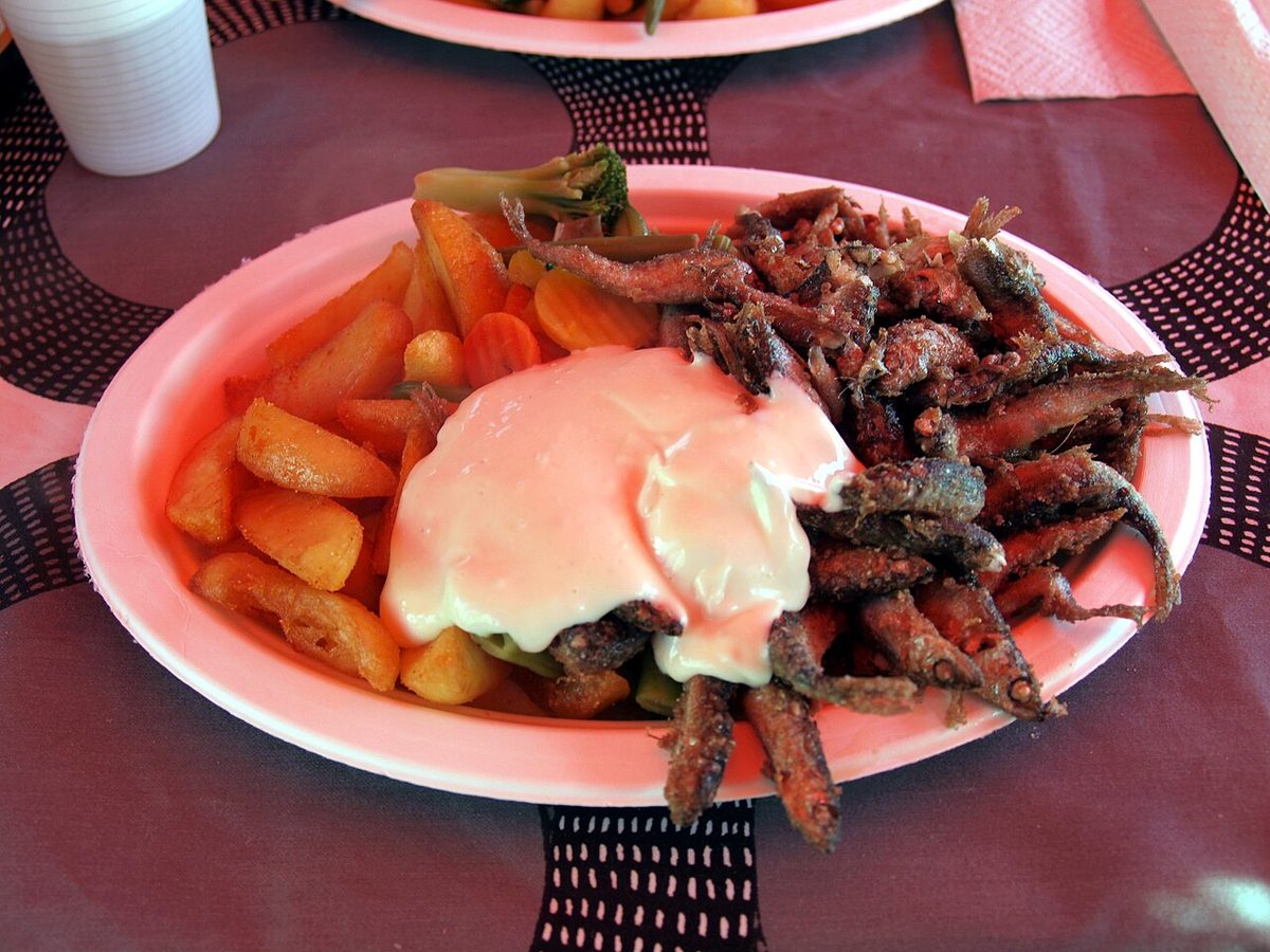 A plate of freshly fried fish with fries and sauce, like the by-weight catch at a Savaneta fish shack