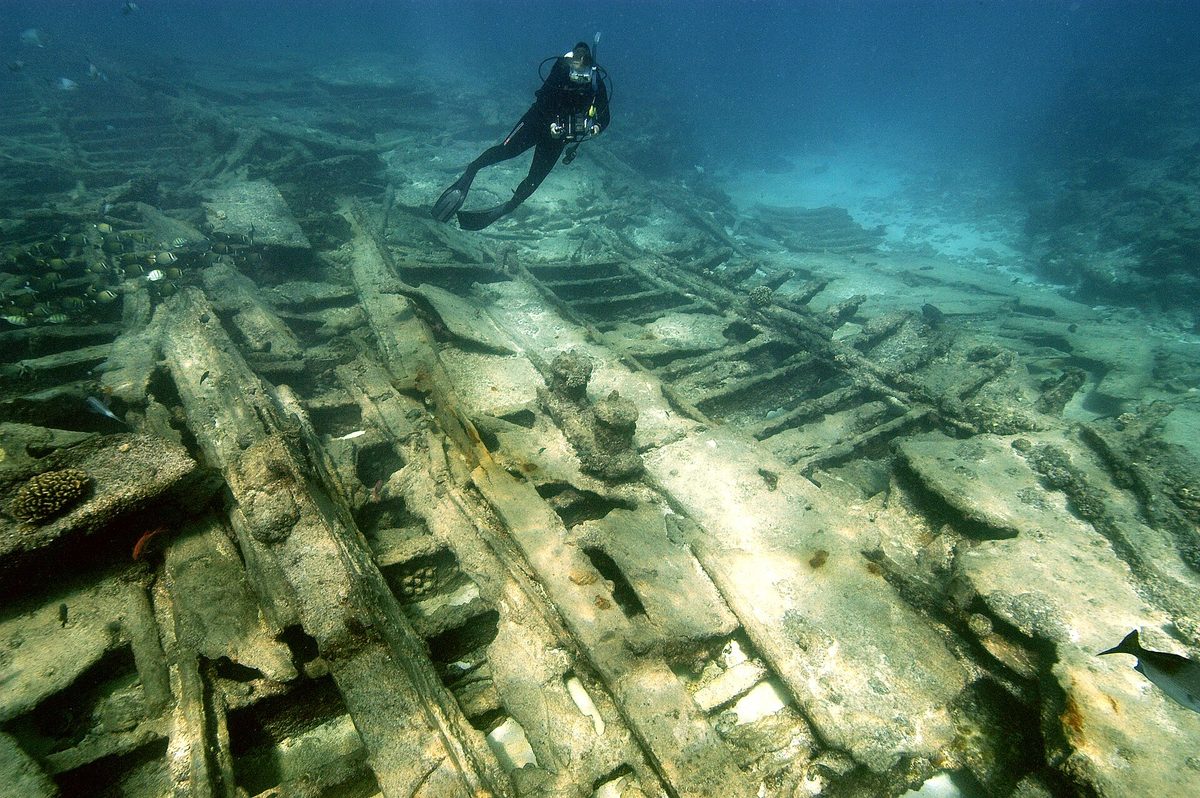 A scuba diver glides over the ribs of a sunken wreck, similar to a dive on the Antilla
