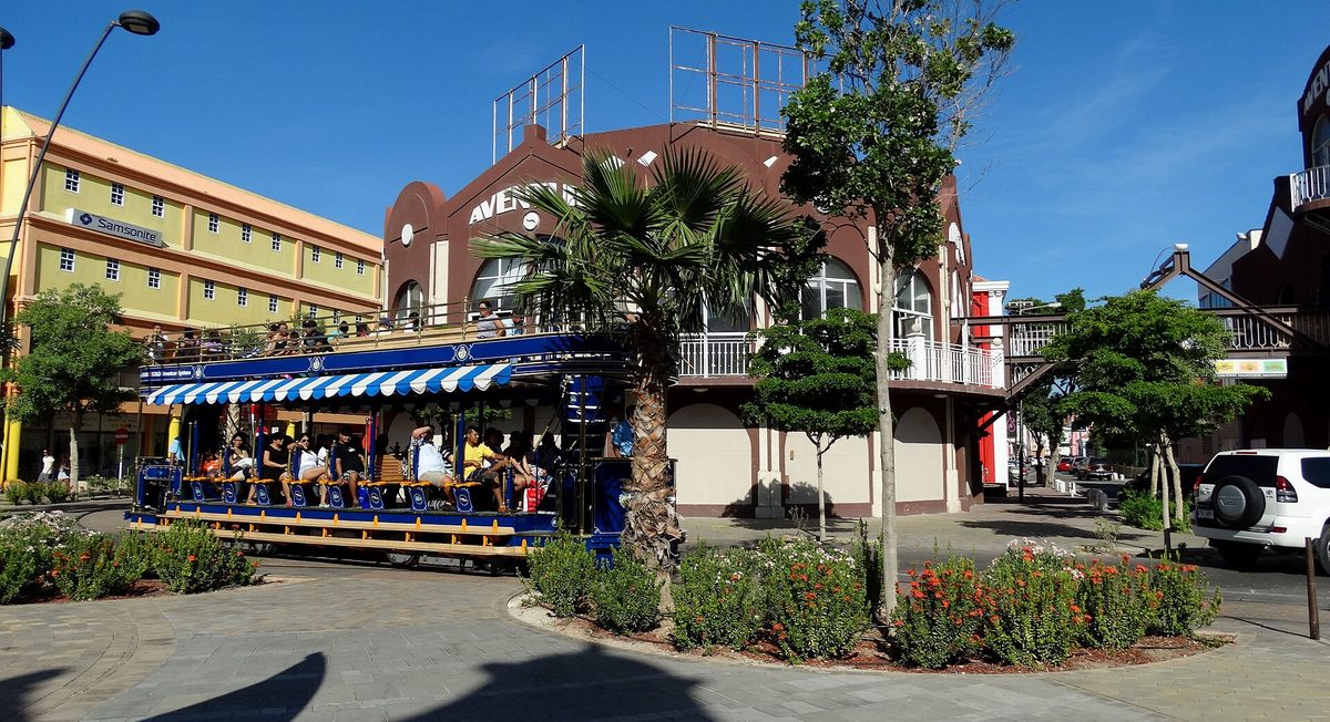 The free Oranjestad streetcar passing downtown shops in Aruba